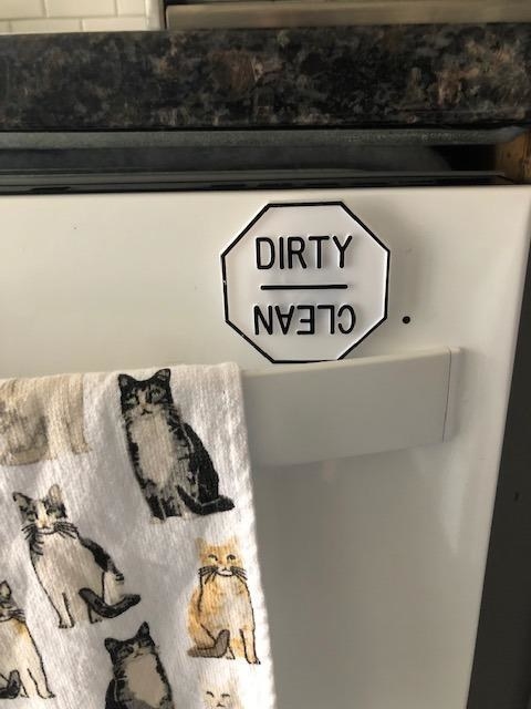 a reviewer photo of the dishwasher magnet on their dishwasher that reads dirty on one side and clean on the other side