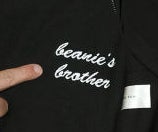 A close-up of Jonah&#x27;s sweatshirt that reads, &quot;Beanie&#x27;s brother&quot; in cursive