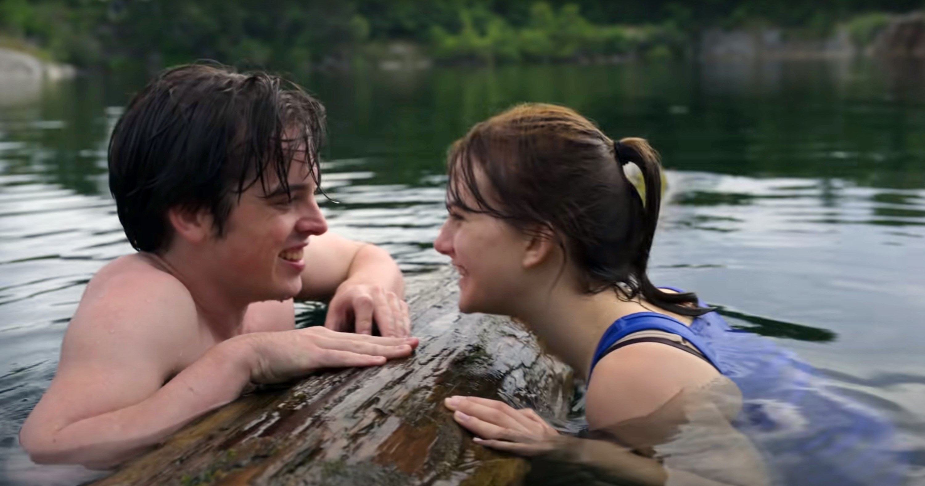 Ferdia Walsh-Peelo and Emilia Jones lean on a log in the water together