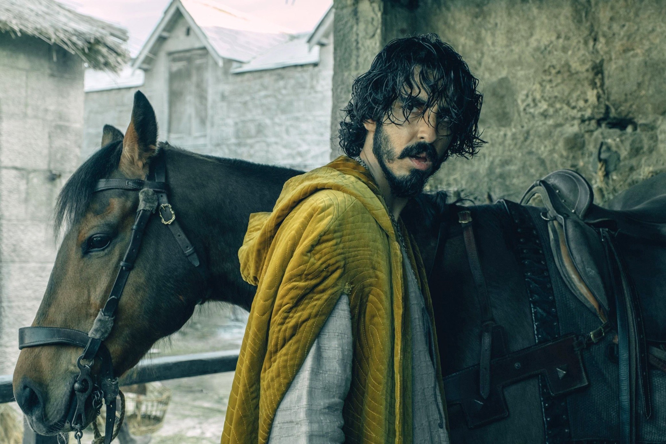 Dev Patel stands by a horse
