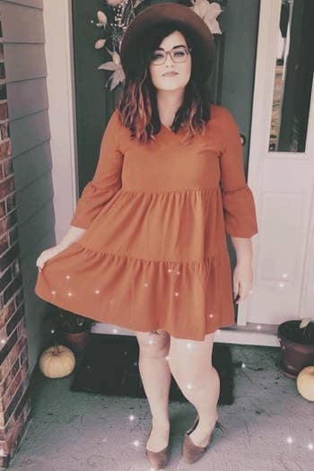 reviewer in orange dress with a hat and flats