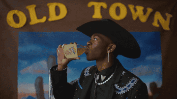 Lil Nas X drinking juice in front of &quot;old town&quot; sign and hitting the woah