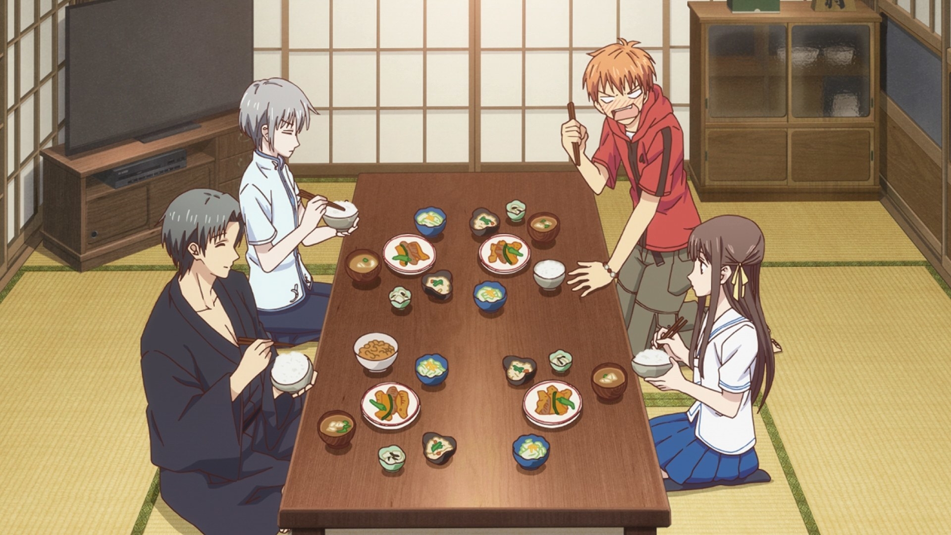 A group of characters eating dinner on a low dining table; they are sitting down with their knees folded or crossed