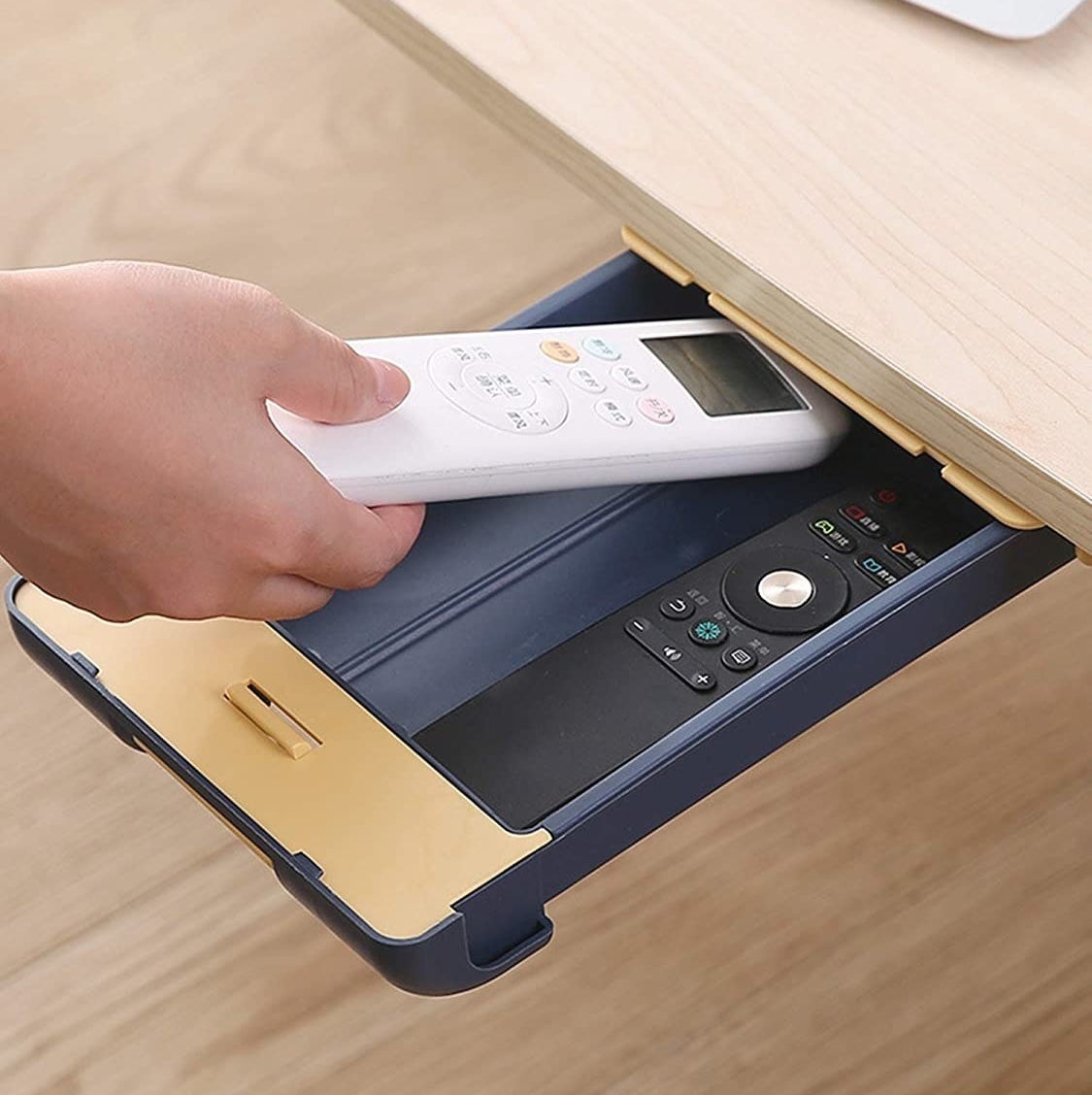 A person putting a remote in the drawer