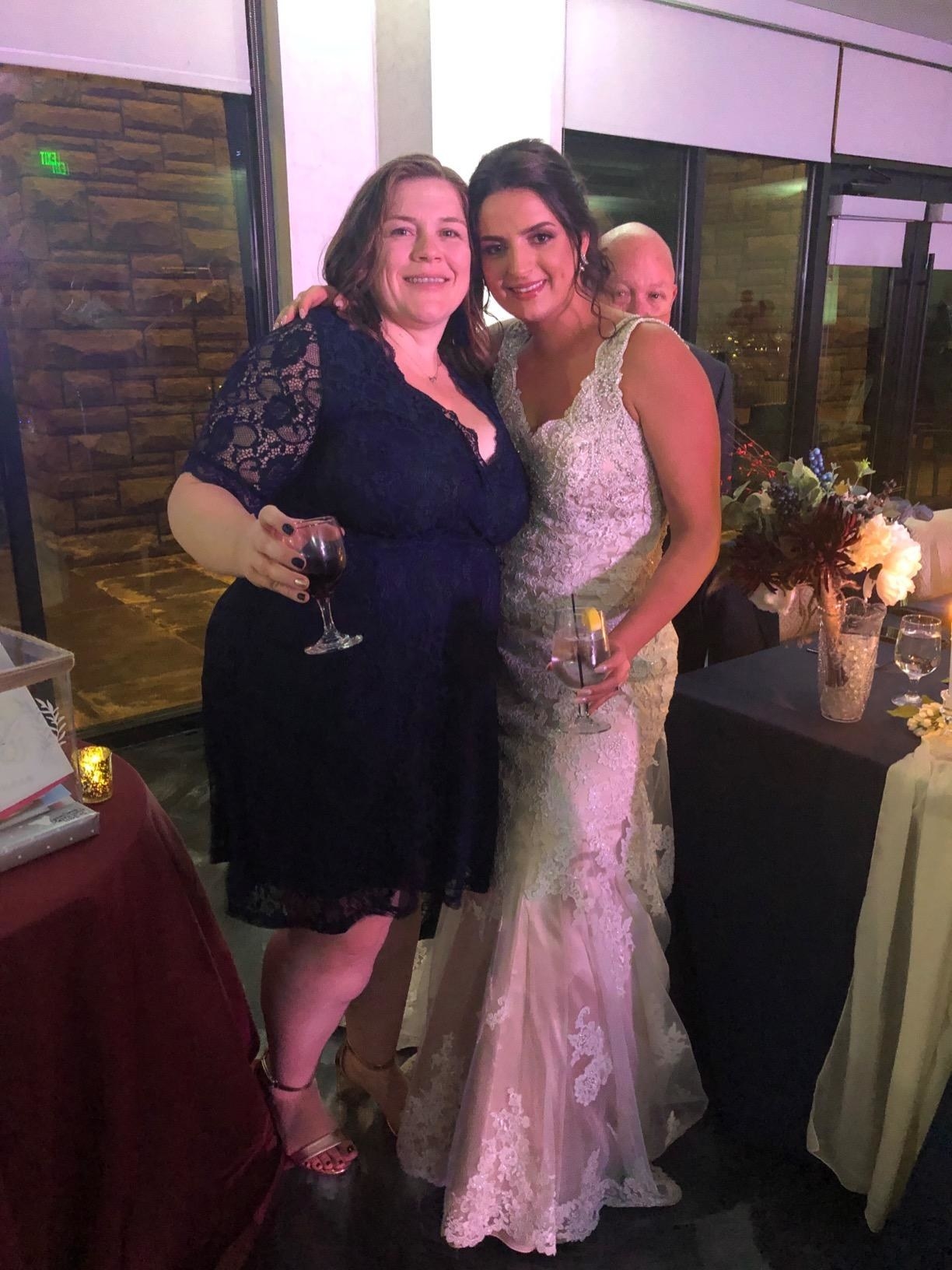reviewer wearing the dress in navy blue posing with a bride