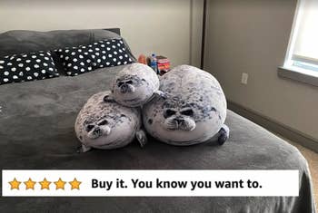 Reviewer's photo showing the seal pillows in three sizes lying on a grey bed