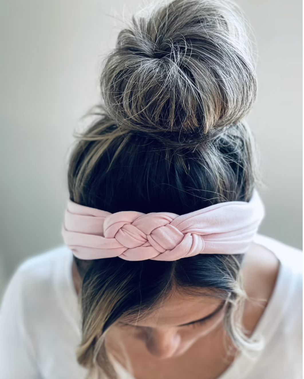 Model wearing a pale pink hair band with a knot design on top 