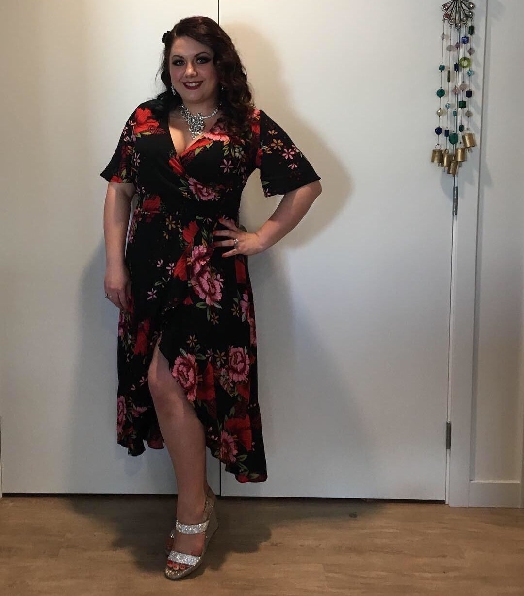 reviewer wearing the dress in black with red flowers and sparkly wedges