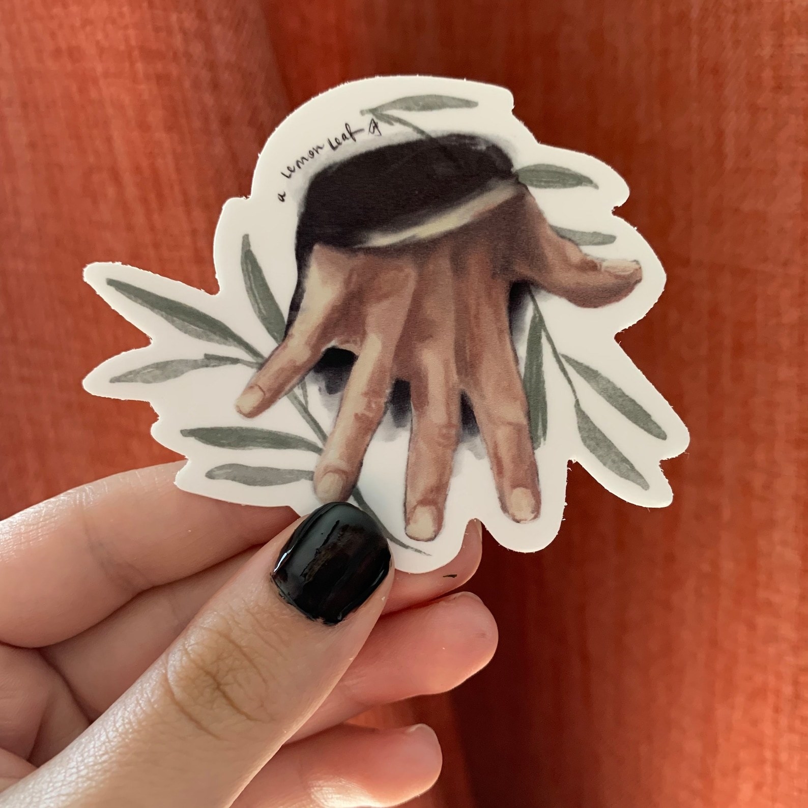 The sticker with a piece of greenery and darcy&#x27;s hand flexed
