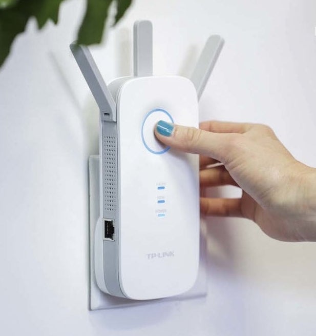 a person pressing a button on the front of the wifi signal extender