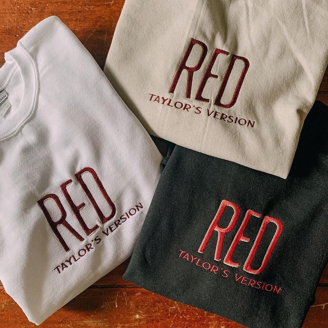 white, beige, and black sweatshirt with embroidered &quot;Red Taylor&#x27;s Version&quot; in red on it