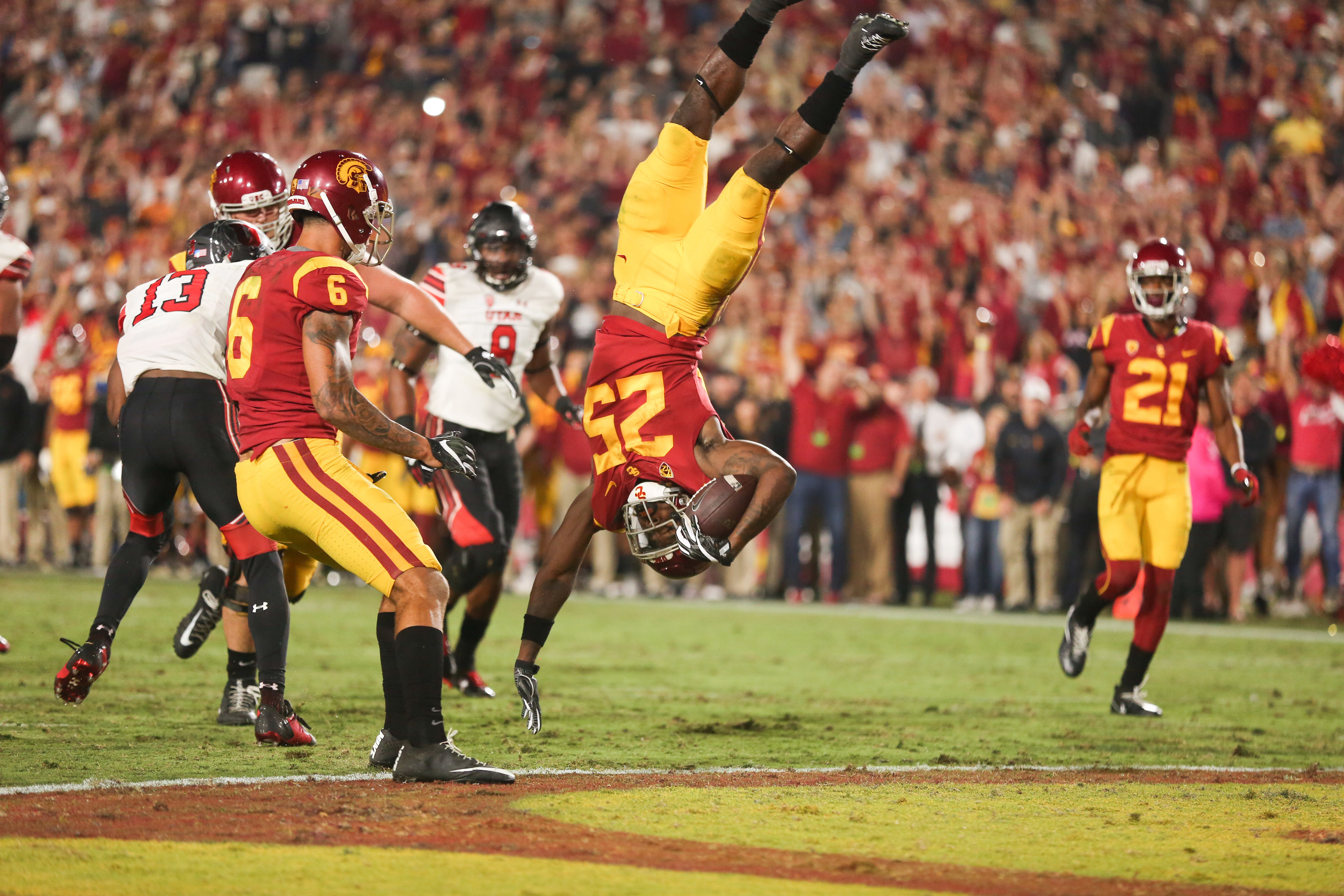 A football player is seen upside down holding a football at a USC game