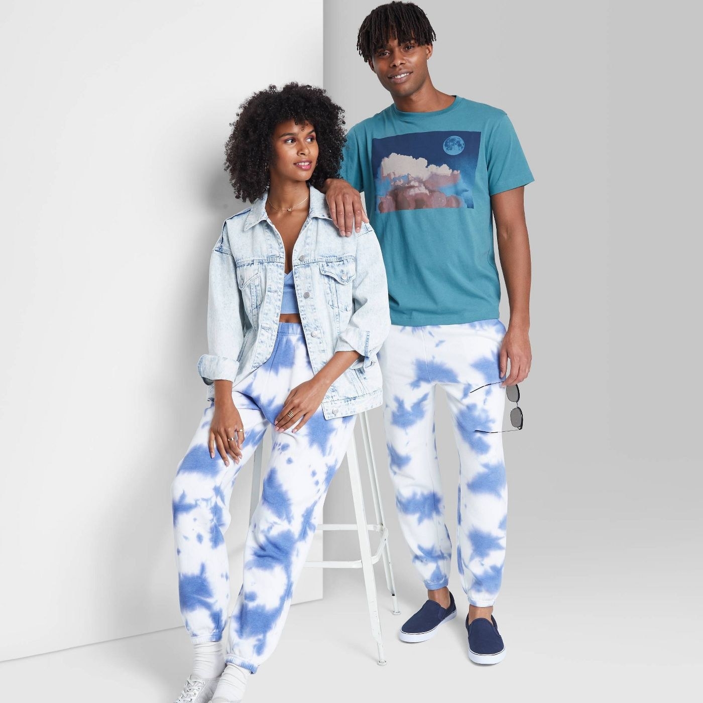 Two models wearing a pair of blue and white tie dye sweatpants
