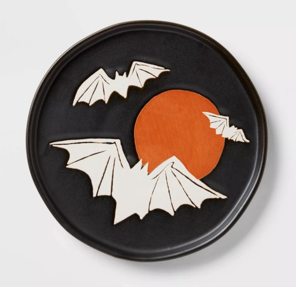 A black serving plate with illustrations of 3 white bats and an orange moon
