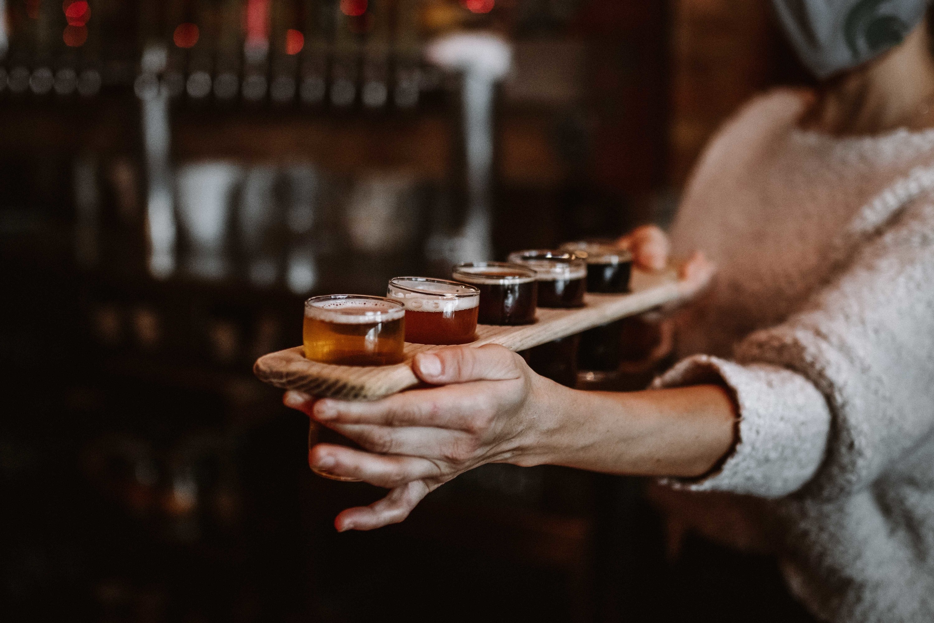 A woman holding a flight of beers.