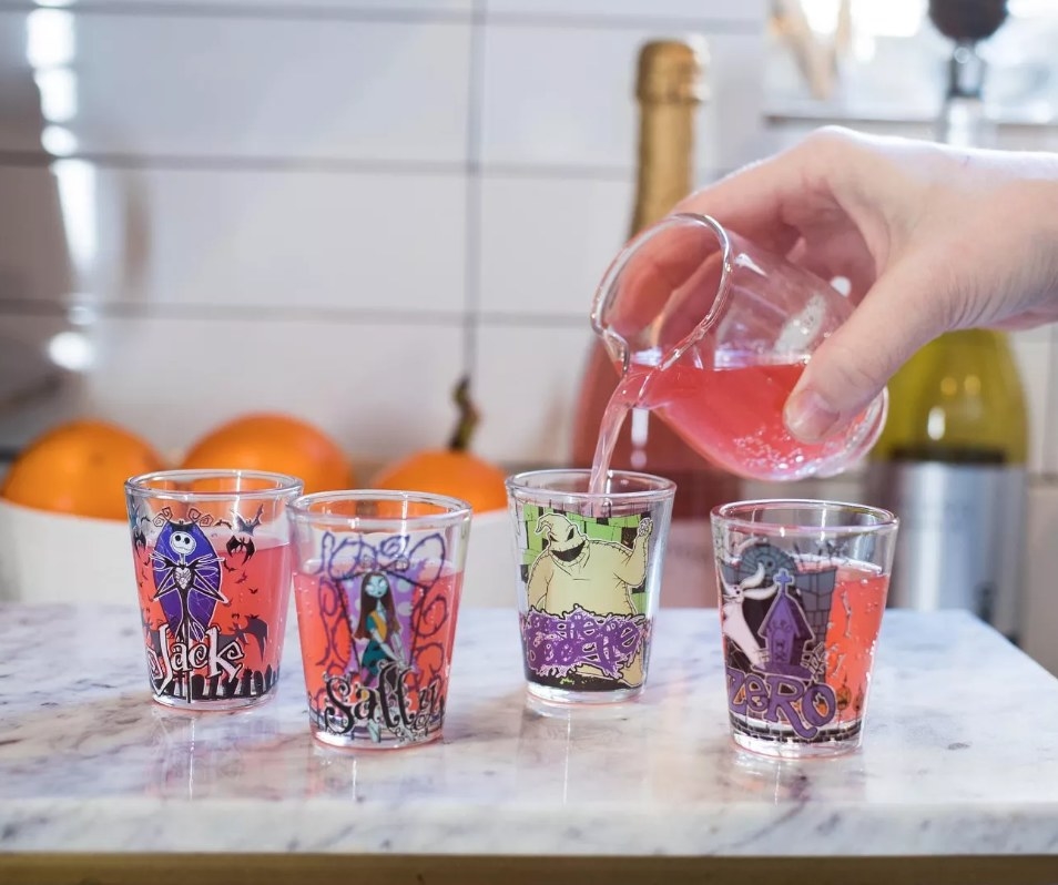 A model pouring a drink into 4 Nightmare Before Christmas mini glasses