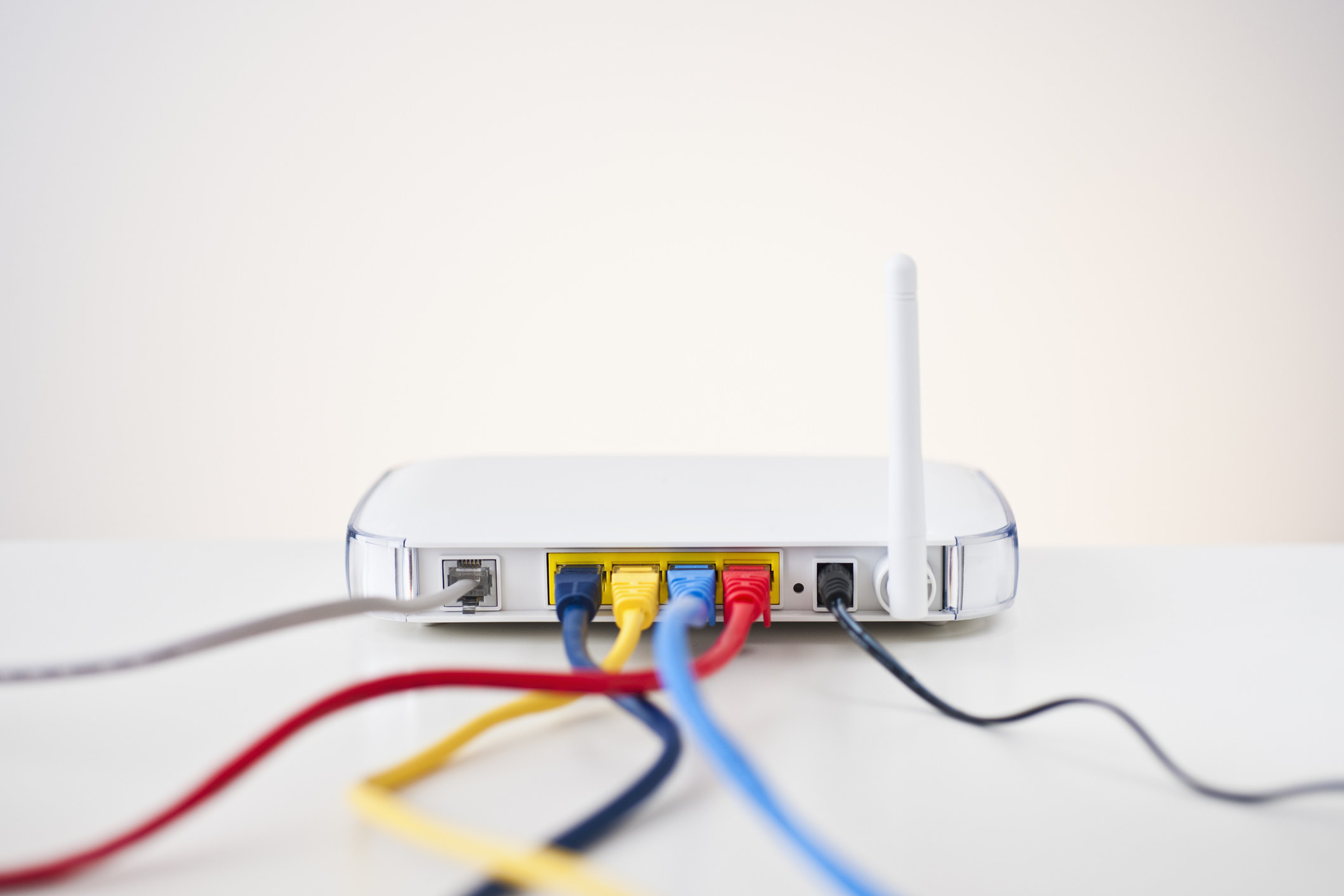 A white router with colorful wires sits on a table.