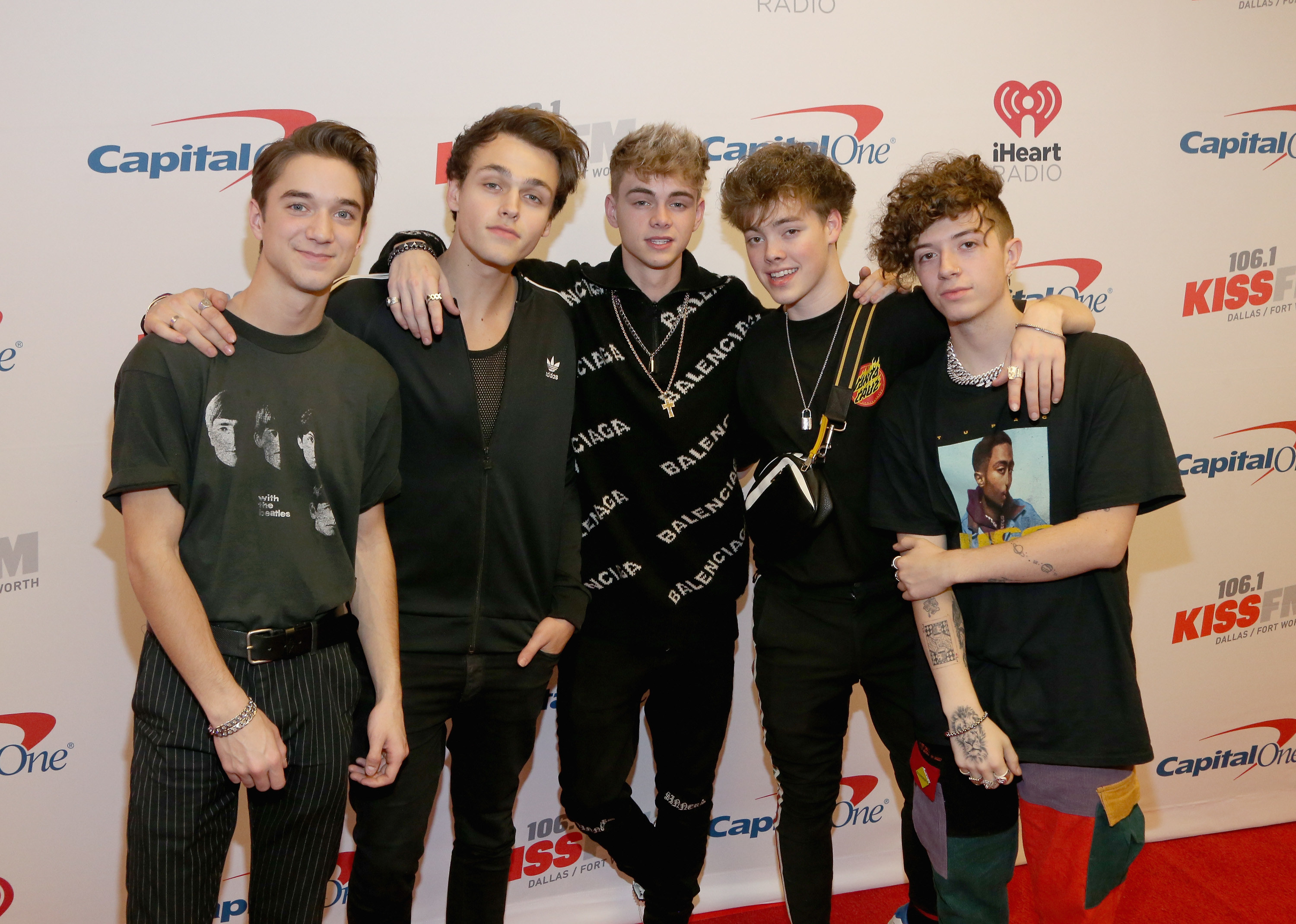 The band poses together on a red carpet