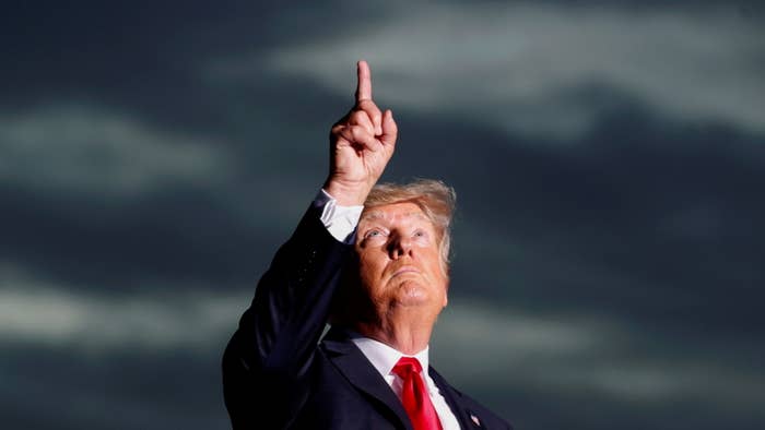 Donald Trump points to a dark, overcast sky