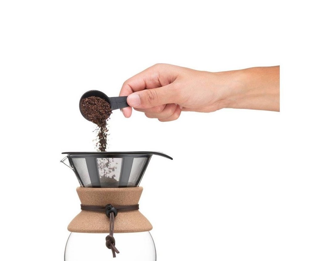 a hand adding coffee to the pour-over coffee maker