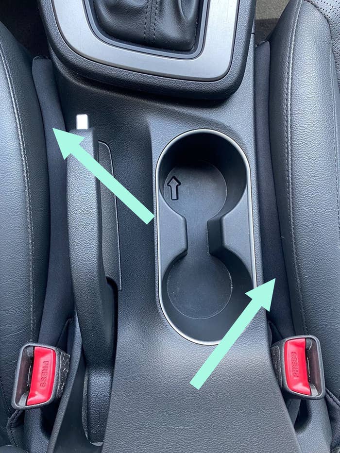 a reviewer photo of the front seat of a car with the seat fillers in the gap between the center console and the car seats