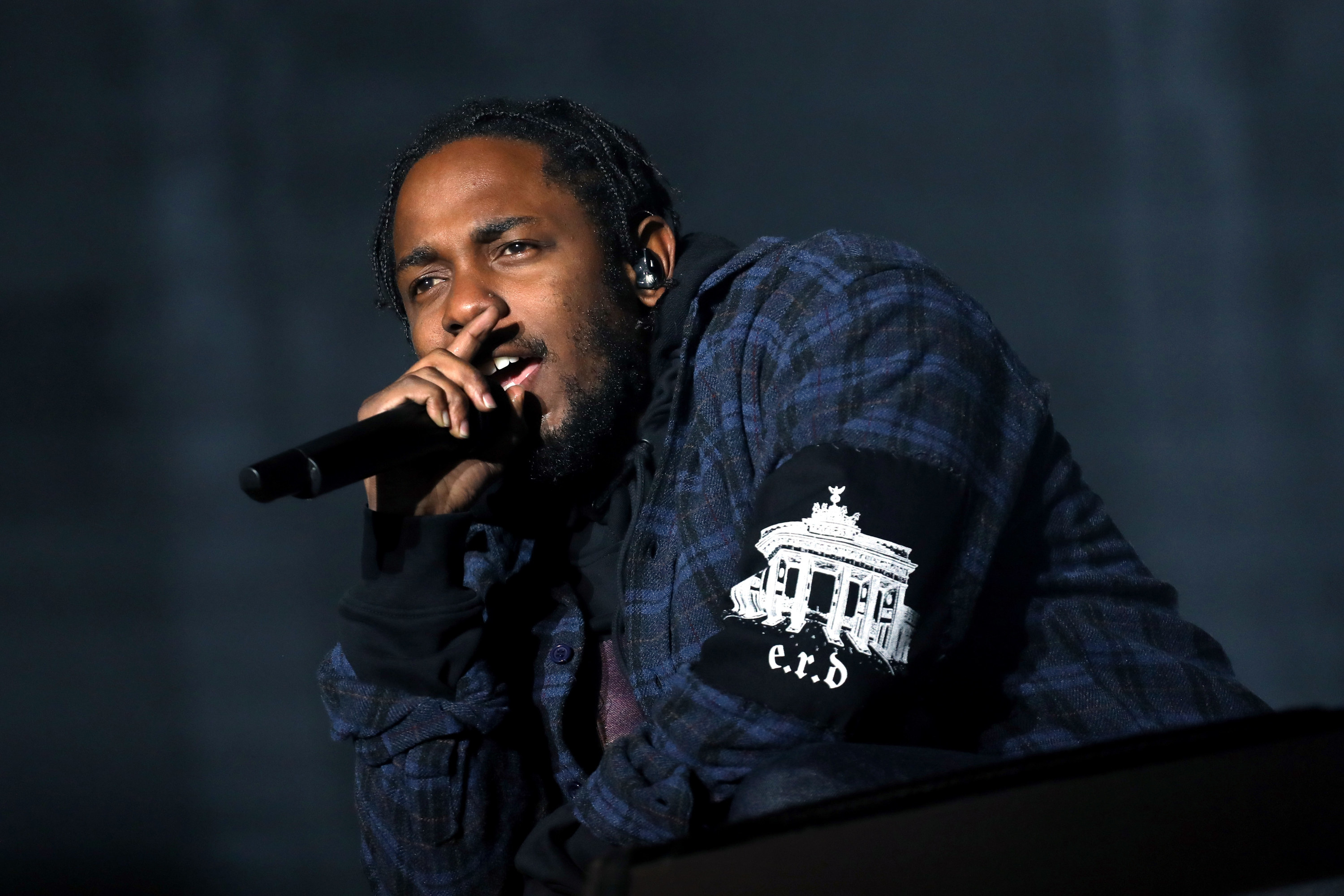 Kendrick Lamar leans on a ledge while singing into a microphone