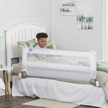 A model in bed reading with the bed rail installed on the bed
