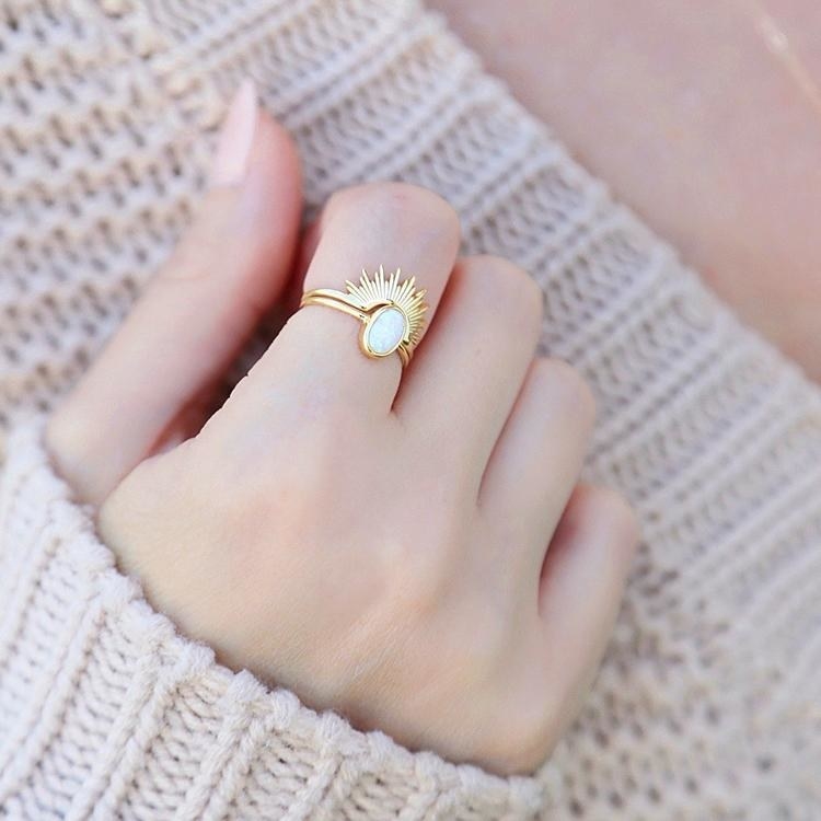 delicate gold rings, one in a sunburst arch shape and other with oval opal