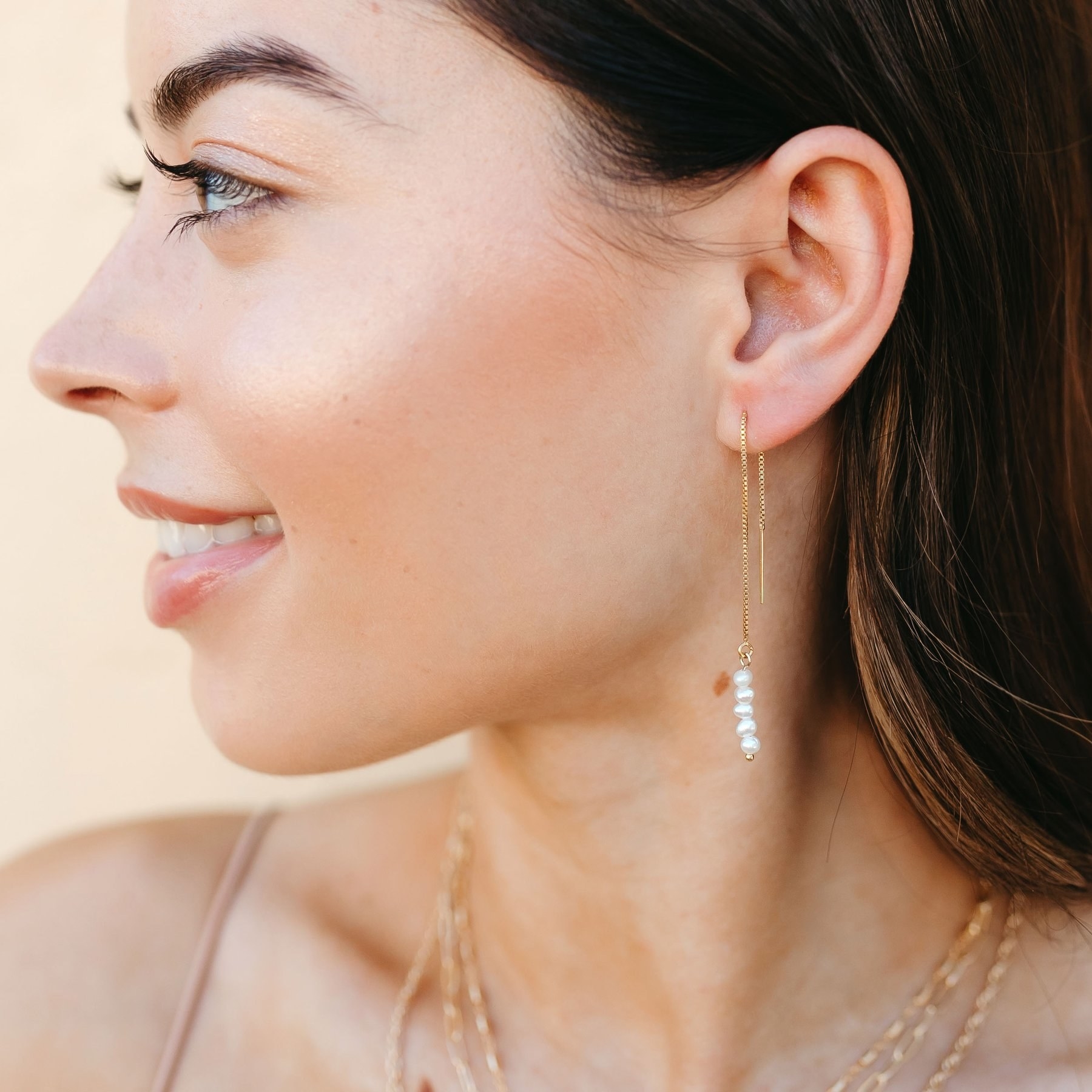 model wearing the threaded earrings with pearls at the end