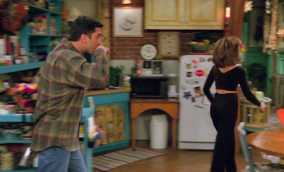 Rachel walking away from Ross, revealing a V-neckline on the back of her shirt