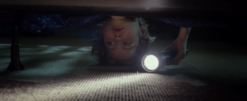Kid looks under his bed with a flashlight