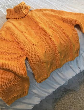 A customer review photo of the sweater laid out on their bed