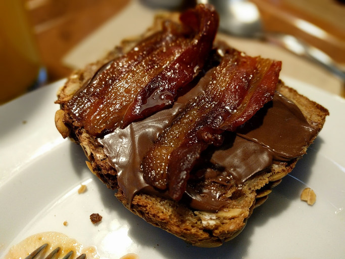 A slice of toast topped with Nutella and bacon