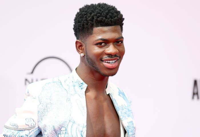 Lil Nas X smiling on a red carpet