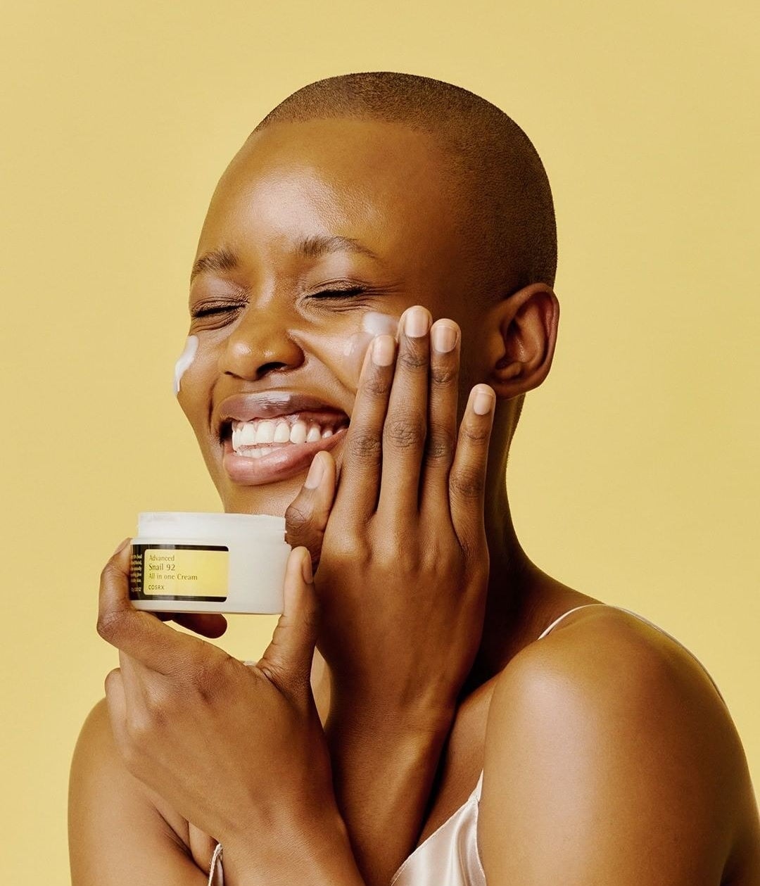 a smiling person applying cream to their face