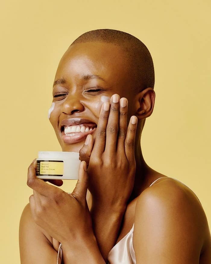 a smiling person applying cream to their face