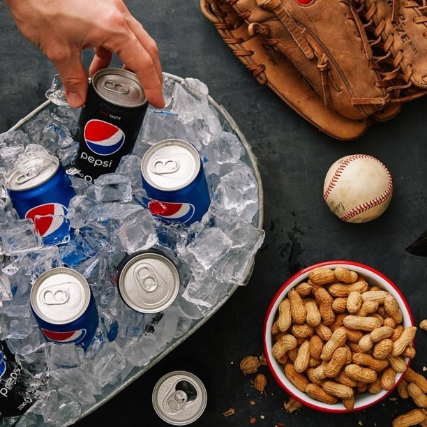 Pepsi cans in a round-shaped cooler next to bowl of peanuts