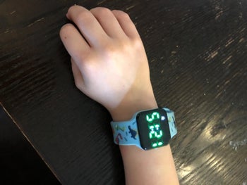 Reviewer's child wearing the watch with the time flashing on the screen