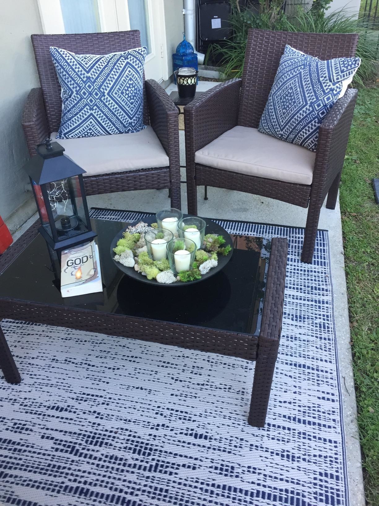 A reviewer's back porch with an some deep brown furniture and a navy and white rug