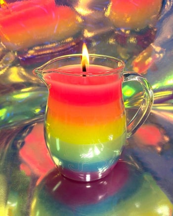Pitcher of rainbow colored wax with lit candle wick