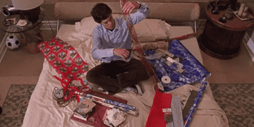 GIF of Seth Cohen wrapping holiday gifts