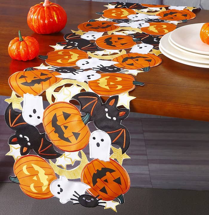 the table runner with jack-o-lanterns, ghosts, spiders, bats, and moons