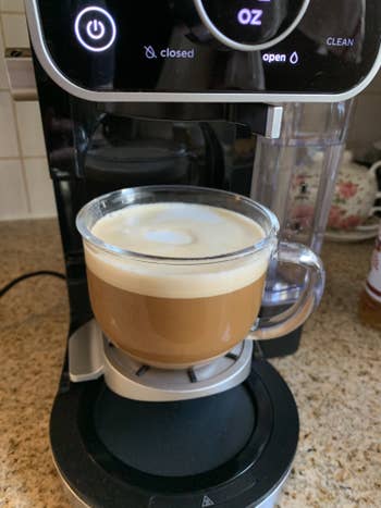 Cup of coffee with frothed milk placed under Ninja DualBrew Pro