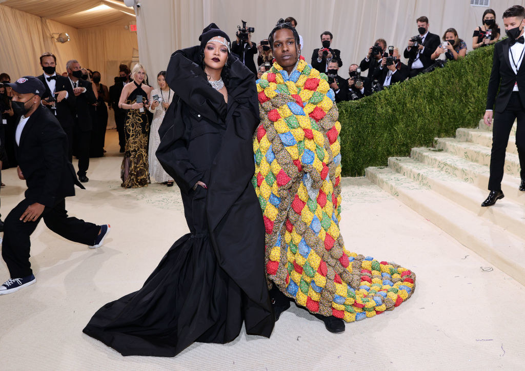 ASAP Rocky wrapped in what appears to be a quilt stands next to Rihanna, who&#x27;s wearing a dark ensemble