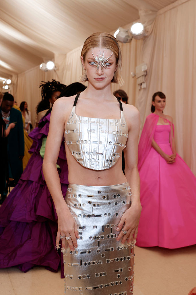 Hunter Schafer wears a Prada two-piece steel plate skirt and top with a spider gem in between her eyes
