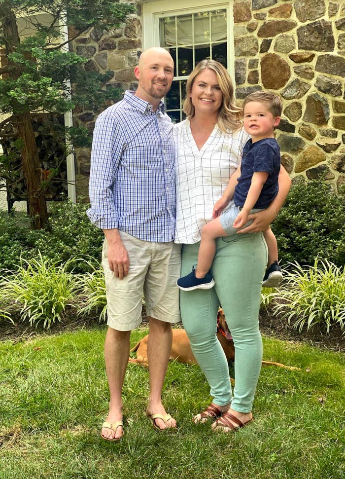 Kayleigh posing for a photo in a front yard with her husband and son