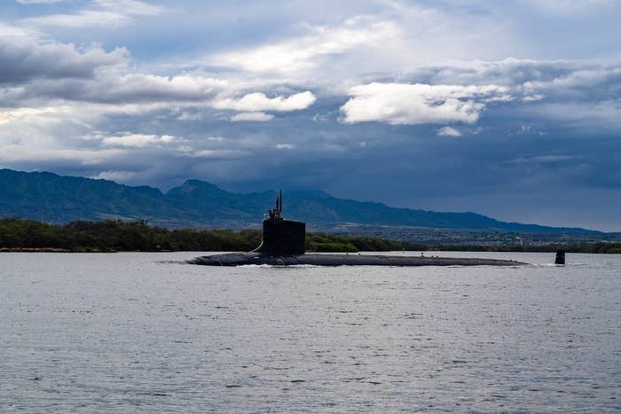 A submarine in the water against a bright blue sky