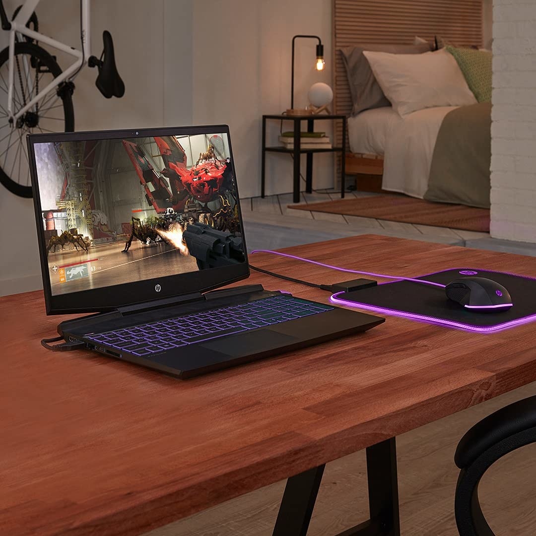 A laptop with a glowing mouse pad beside it