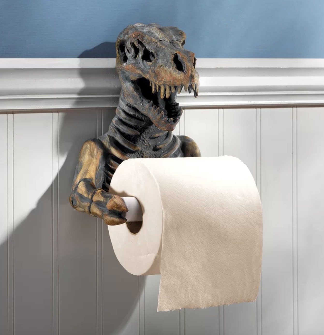 The toilet paper holder is the chest and arms of a dino and its large face and mouth