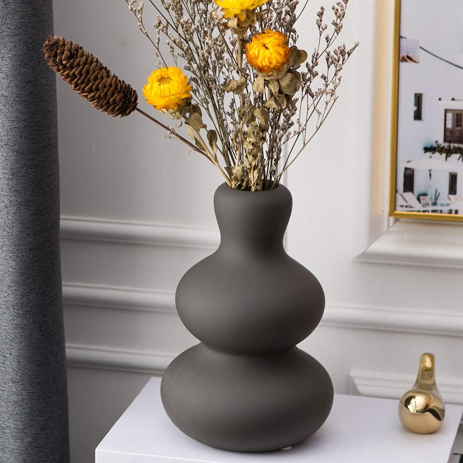 the brown ceramic vase with flowers in it